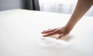 Hand, die über eine weiche Matratze fährt